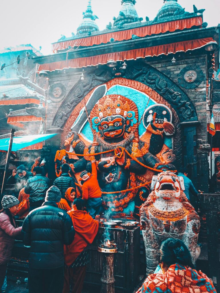 Colorful scene at Kal Bhairav Temple, Kathmandu, showcasing religious reverence and vibrant decorations.
