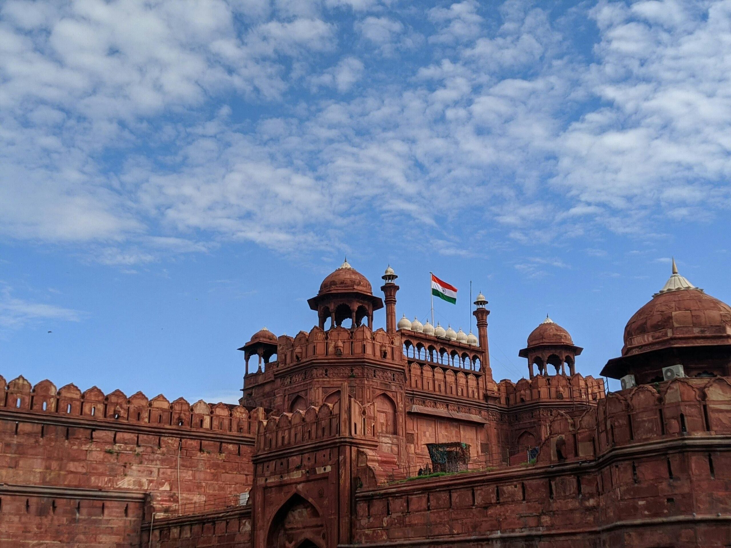Stunning photo of Red Fort, Delhi with the Indian flag against a blue sky.