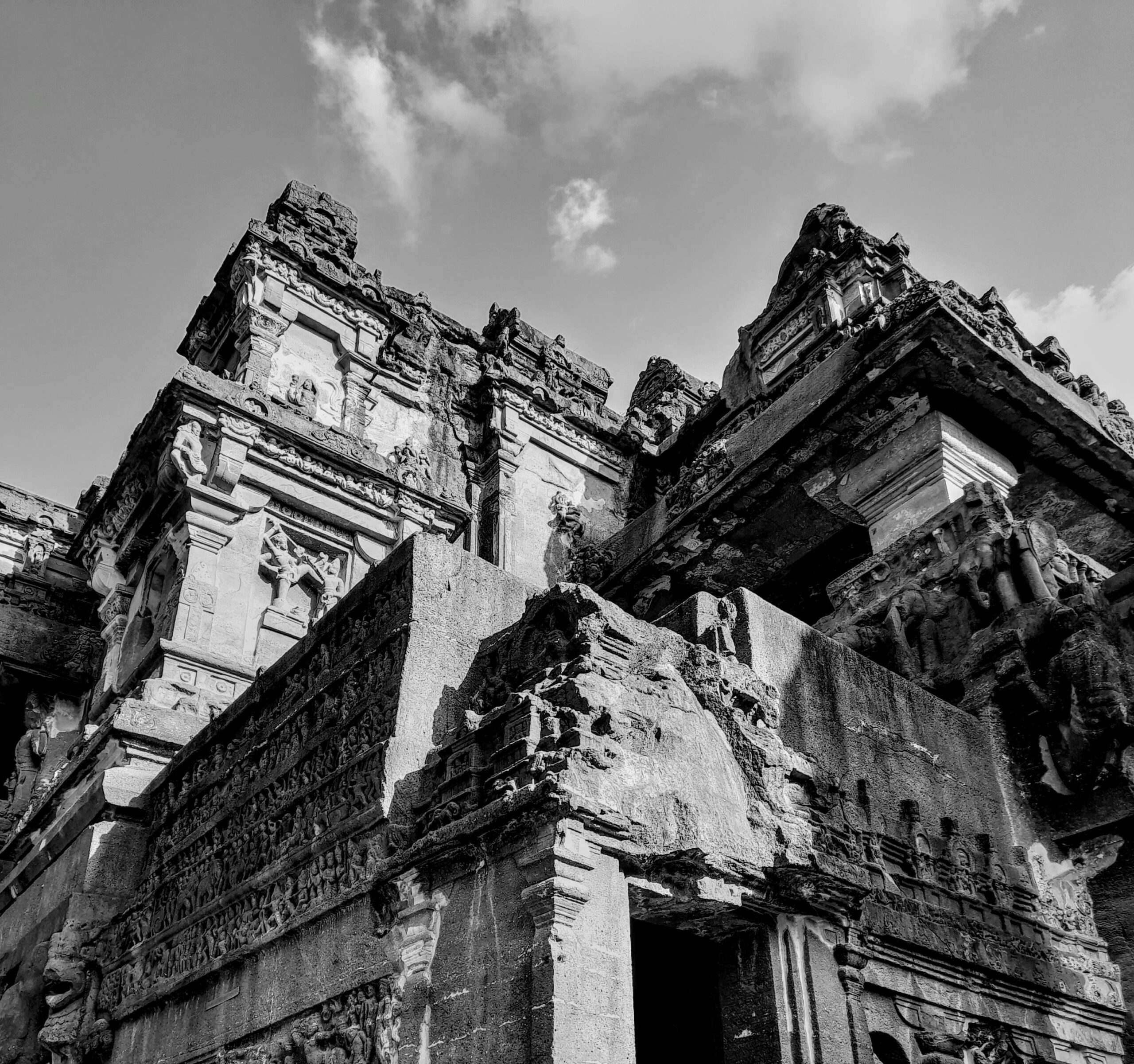 Black and white photo of intricate ancient temple architecture with cloudy sky background.