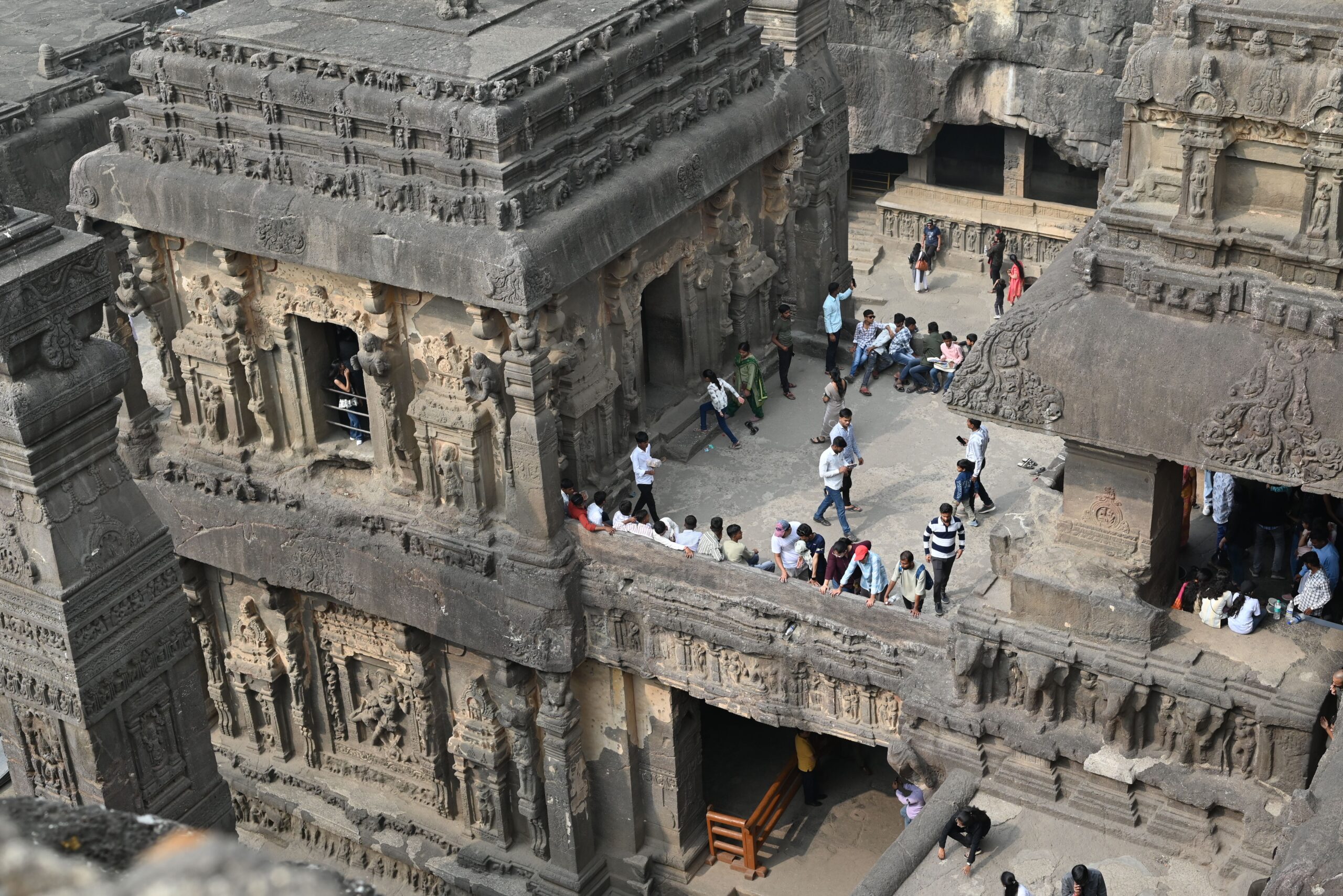 Aerial view of the ancient Kailasa Temple at Ellora Caves, bustling with tourists.