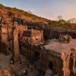 A breathtaking view of the ancient Ellora Caves captured at sunset, showcasing intricate stone carvings.